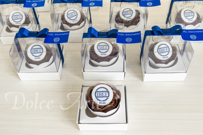 Cupcakes decorados com a logo em caixa de acetato, fita e tag personalizada para evento corporativo